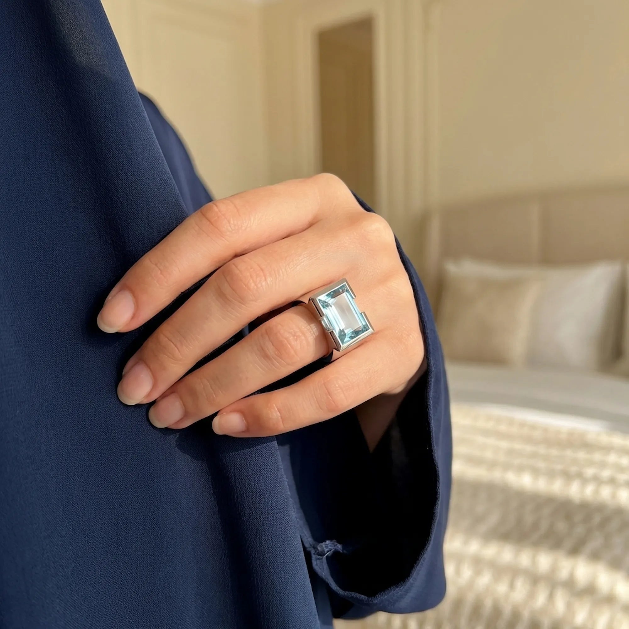 Elegant woman wearing a snag-free 925 sterling silver bezel sky blue topaz ring against a navy blue abaya, perfect for daily wear in Dubai.