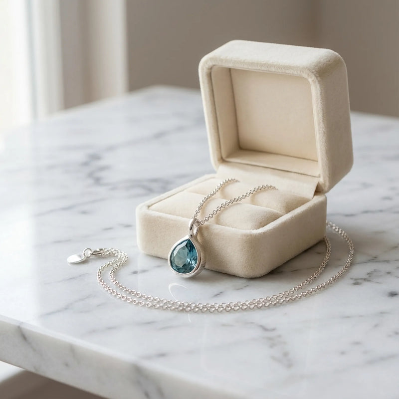 Sky blue topaz teardrop pendant necklace in 925 sterling silver beside cream velvet gift box on marble — Luna Dura Dubai