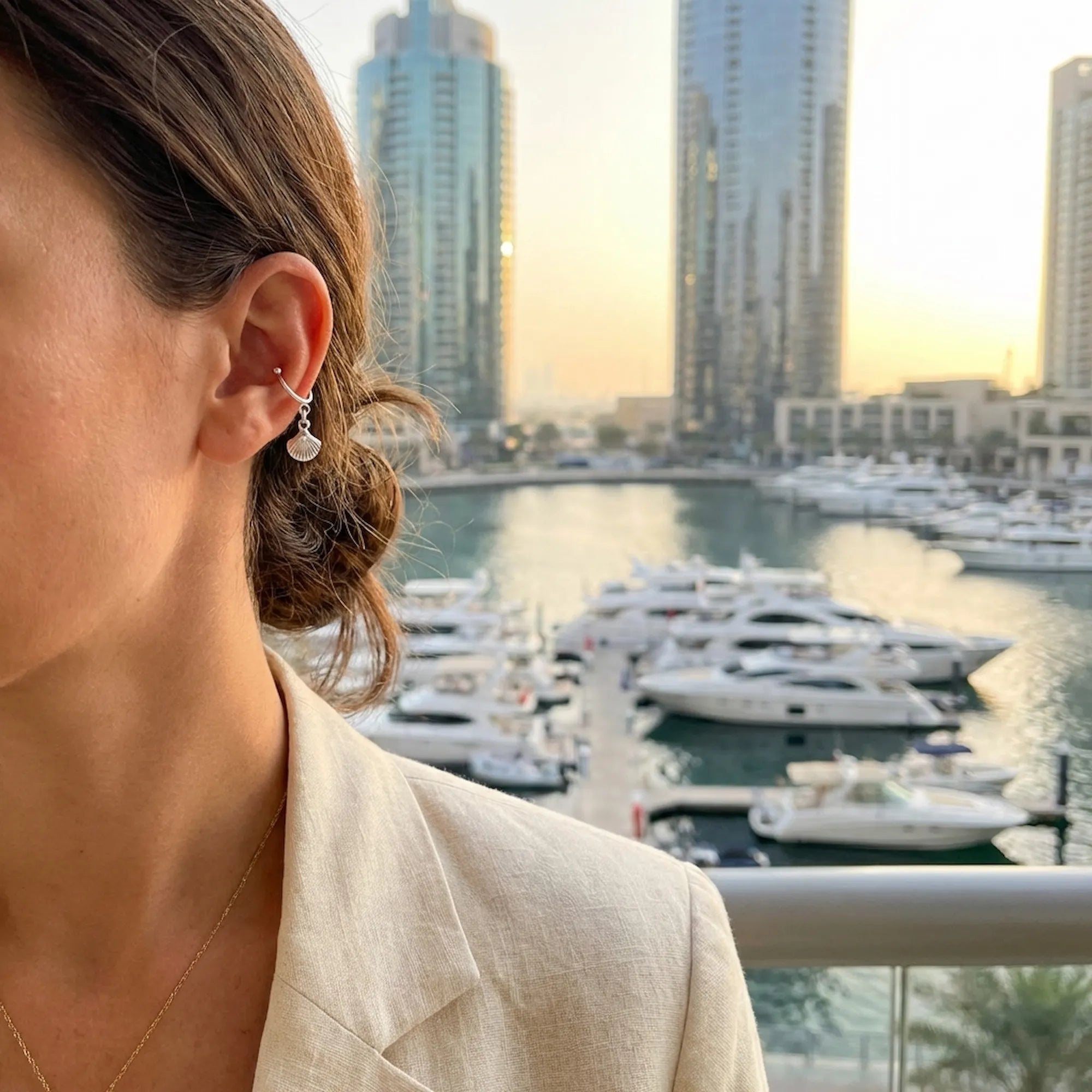 Model wearing a non-pierced 925 sterling silver ear cuff from Luna Dura, with a luxury Dubai waterfront background.
