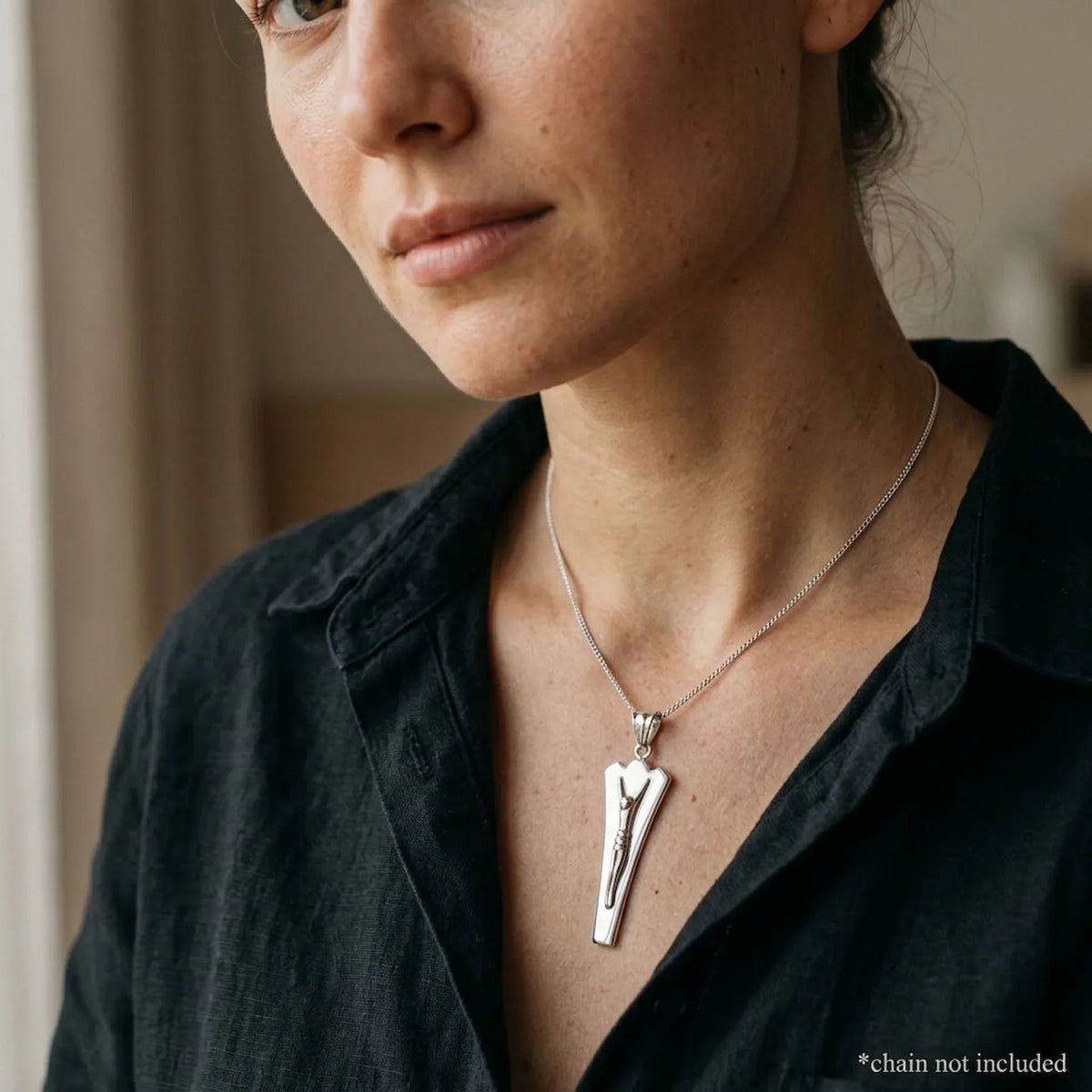 Woman wearing a mirror-polished modern Christian pendant with embossed Christ figure, chain not included