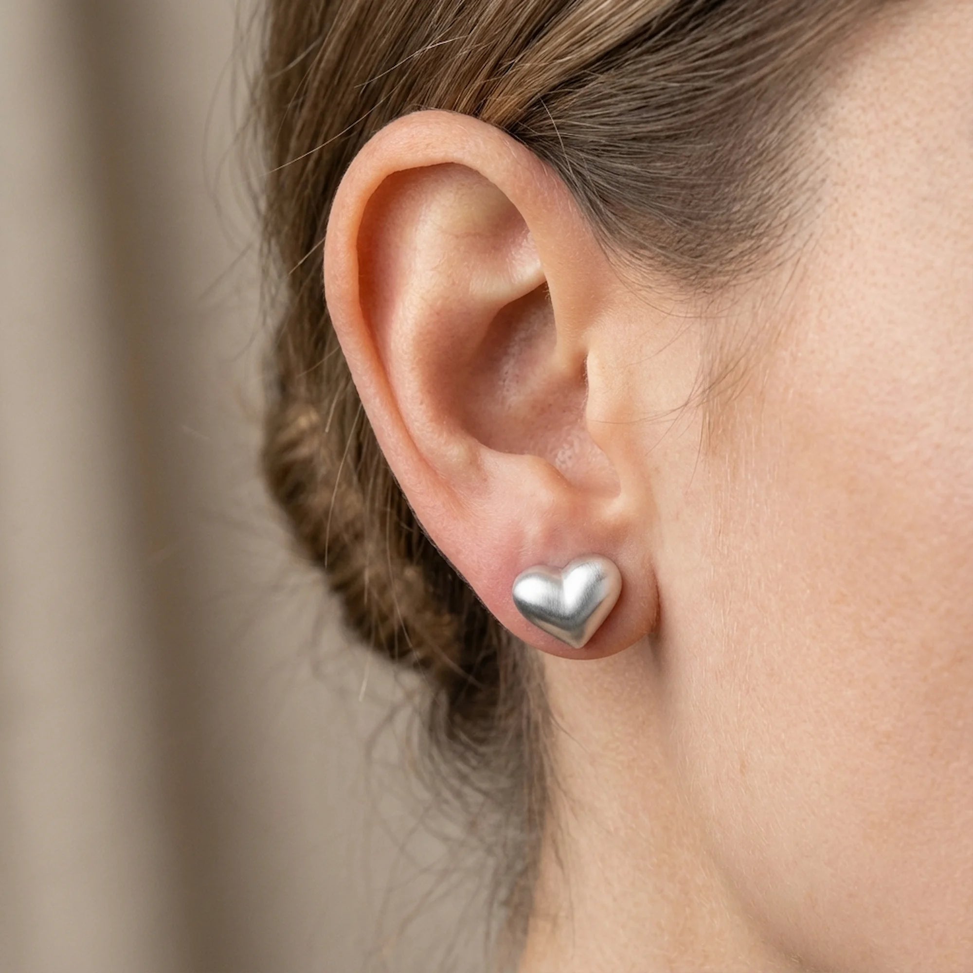 Close-up of woman wearing silver heart stud earring in Dubai