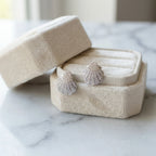 Silver shell earrings displayed inside a beige velvet presentation box resting on a marble surface in Dubai.