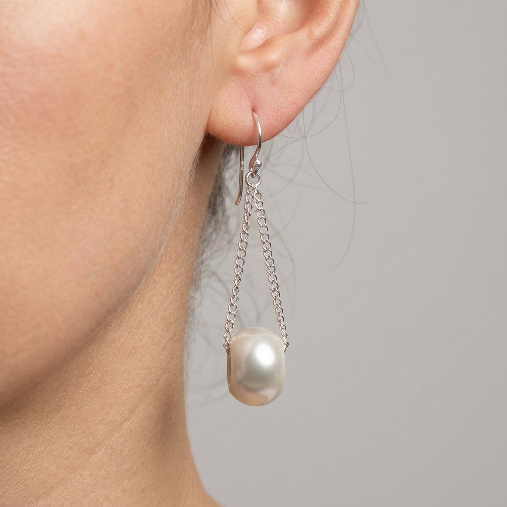 white Pearl earring with chain on a neutral background