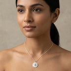 Woman wearing a silver necklace wedjat eye of horus pendant against a neutral background