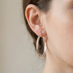 Classic polished silver hoops 5 mm wide, handmade in Dubai worn by model blurred background 