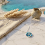 Necklace with a blue pendant on a marble surface with a scenic background