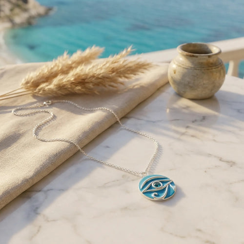 Necklace with a blue pendant on a marble surface with a scenic background