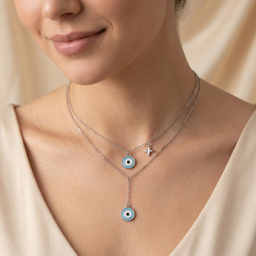 Close-up of a model wearing a silver dainty necklace with evil eye-shaped charms in Dubai on a beige background.
