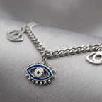 Macro Photo Silver chain necklace with eye-shaped charm on a gray surface