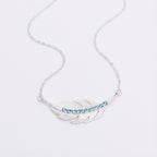 Angle photo of light weight Silver necklace with a feather-shaped pendant featuring blue stones on a light gray background UAE