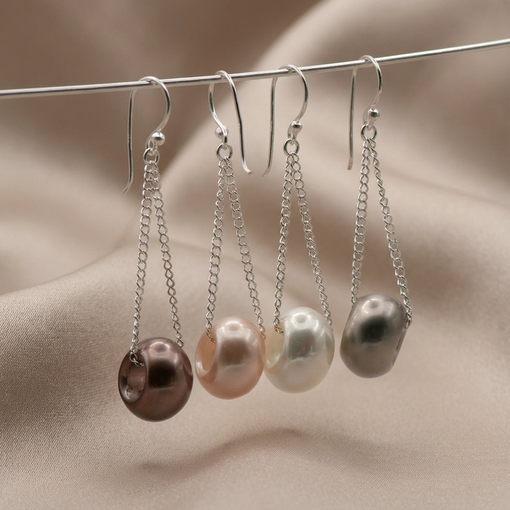 Four pearl earrings on a wire against a beige fabric background