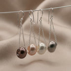 Four pearl earrings on a wire against a beige fabric background