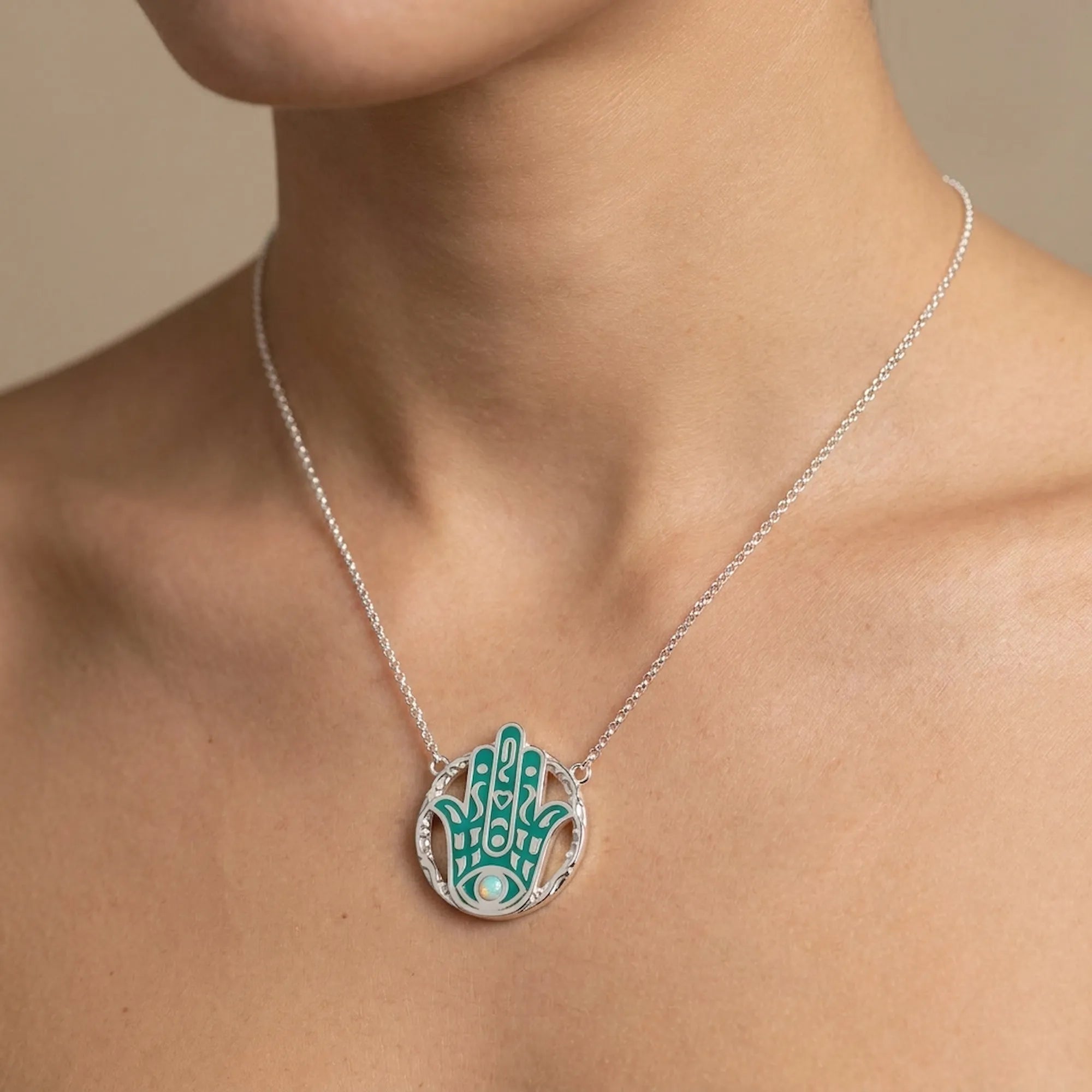 Necklace with a green and silver pendant on a model neck against a neutral background