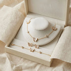 18K gold plated mother of pearl butterfly necklace, bracelet, and stud earrings arranged in an ivory luxury gift box.