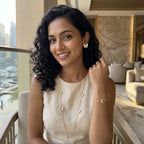 Woman smiling while wearing 18K gold plated mother of pearl butterfly station necklace, studs, and bracelet in Dubai.