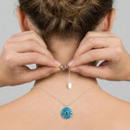 Product Usage Image Model wearing a silver necklace with a blue eye pendant, adjusting spring lock closer.
