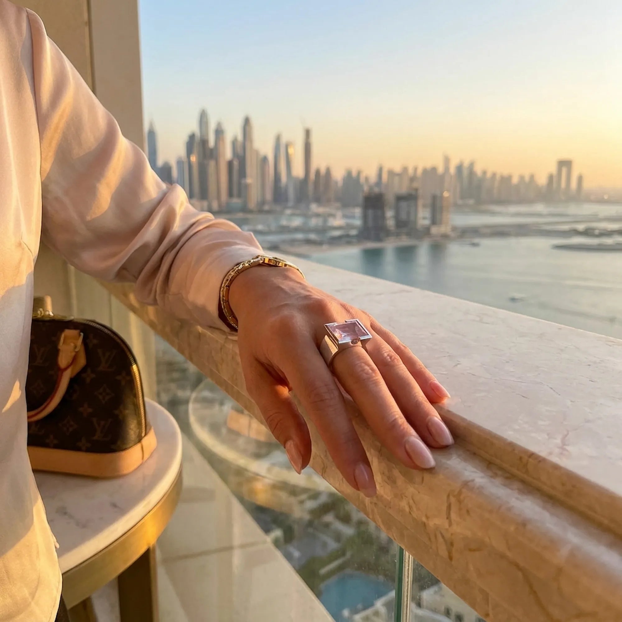 Model hand with rose quartz ring with dubai marina cityscape in the background 