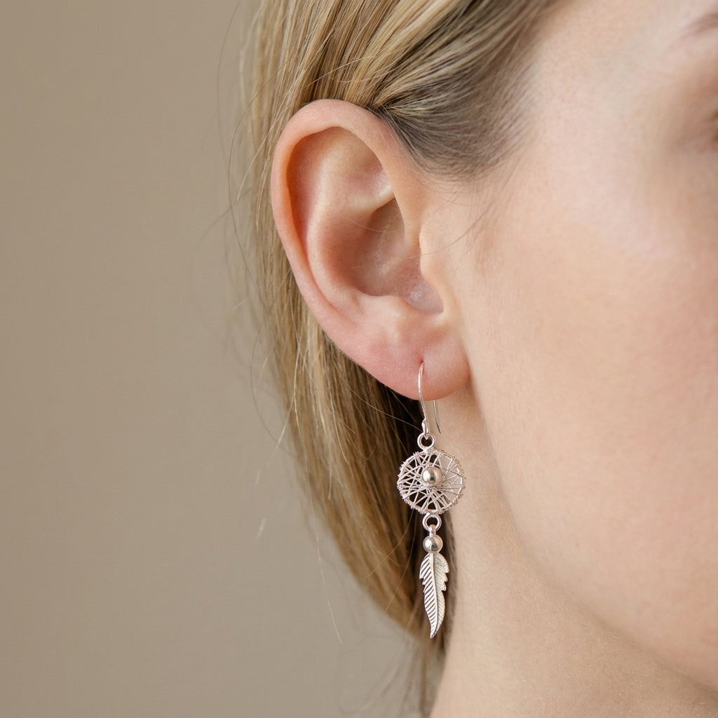 Silver earring with feather detail worn by a model against a neutral background at Luna Dura studio SZR.