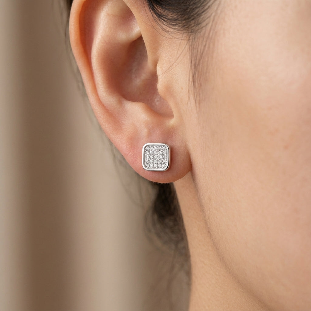 Close-up of an ear wearing a silver square earring with embedded stones Dubai.