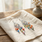 Silver dangle earrings with colorful beads on a light fabric surface