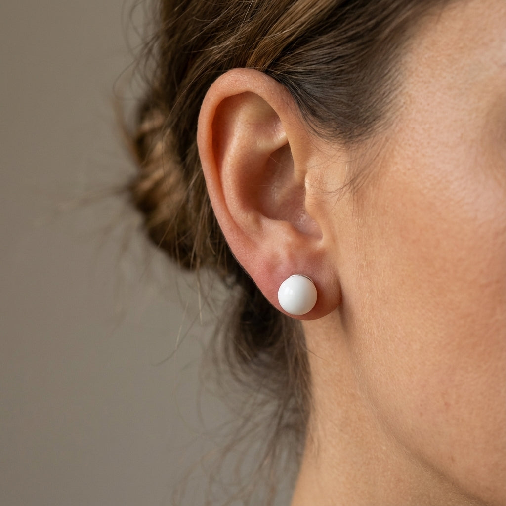 Close-up of an ear wearing a white spherical earring Pure elegance in minimalist silver form