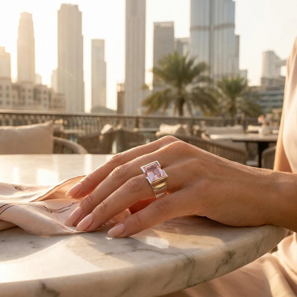 Model hand with a rose quartz on a marble surface with Dubai cityscape in the background