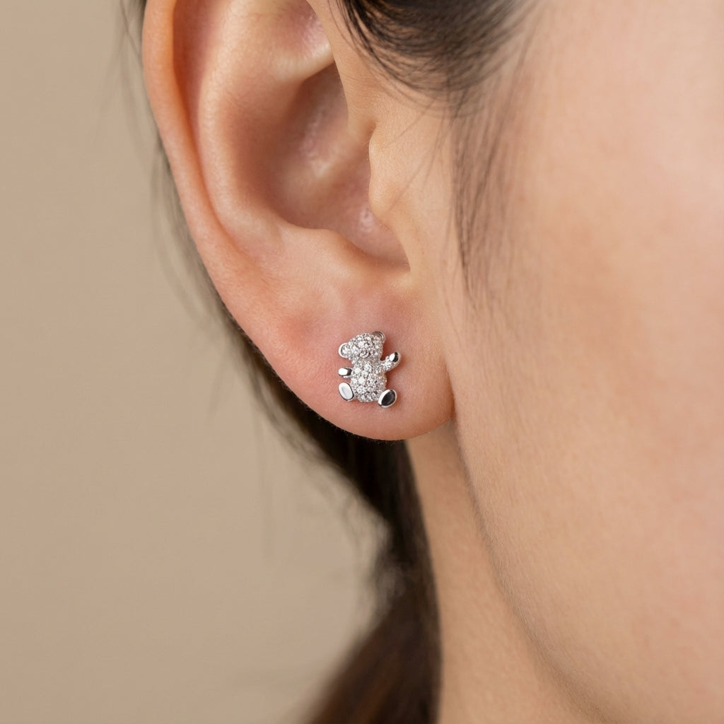 Close-up of an ear wearing Sparkling teddy bear earrings symbolizing love and joy