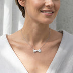 Woman wearing a 925 silver bow pendant necklace with a cubic zirconia stone, styled in a lifestyle setting in Dubai.