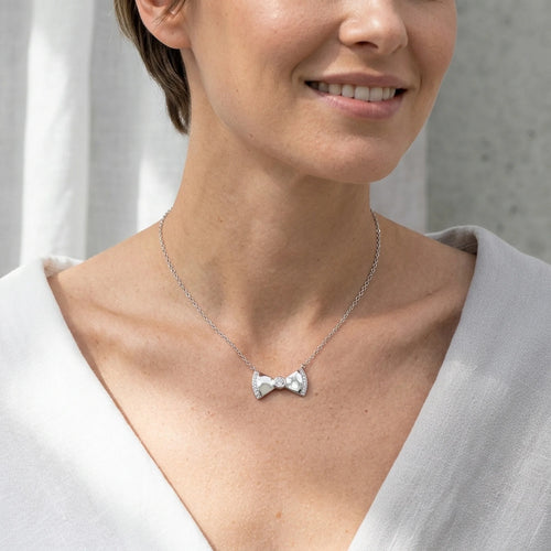 Woman wearing a 925 silver bow pendant necklace with a cubic zirconia stone, styled in a lifestyle setting in Dubai.