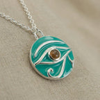 Macro Detail Image Teal pendant with a  yellow gemstone on a beige fabric background