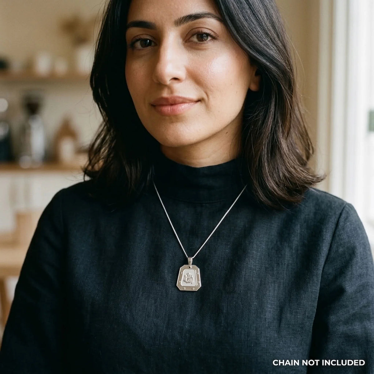 Woman wearing a silver Allah pendant with six screw-head motifs and satin centre; styling chain not included.
