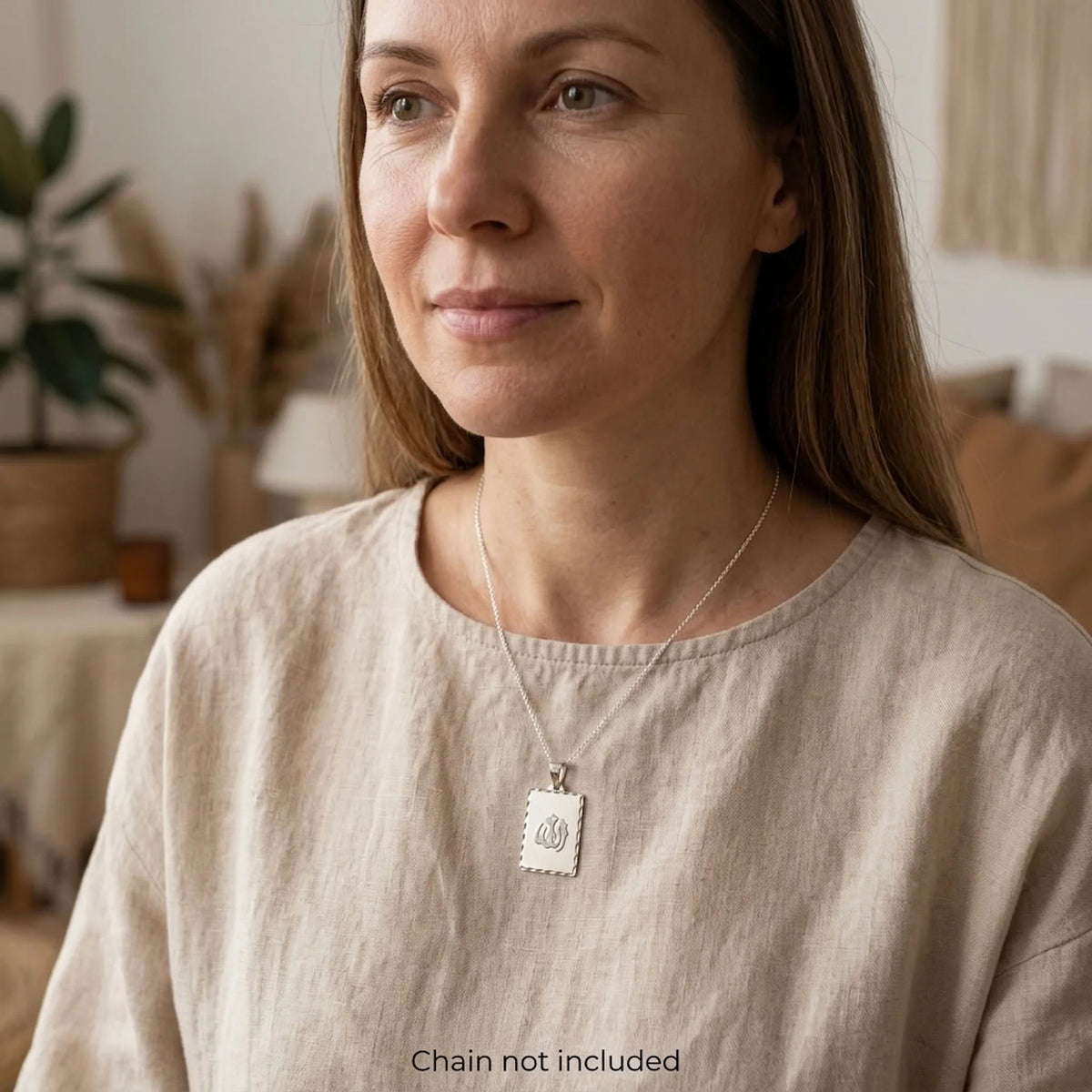 Woman wearing the rhodium-plated Allah name silver pendant on a styling chain, sold separately.