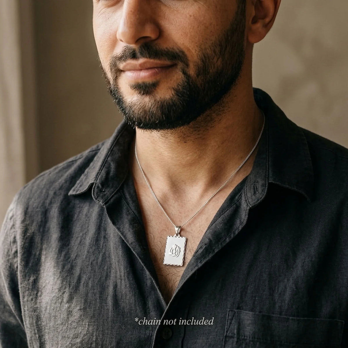 Man wearing the rectangular Allah name pendant in silver on a styling chain, which is not included with the pendant.
