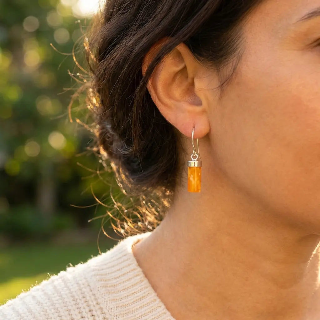 Detailed close-up of a woman wearing a honey amber drop earring, showing the translucent gemstone texture and sterling silver hardware