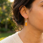 Detailed close-up of a woman wearing a honey amber drop earring, showing the translucent gemstone texture and sterling silver hardware