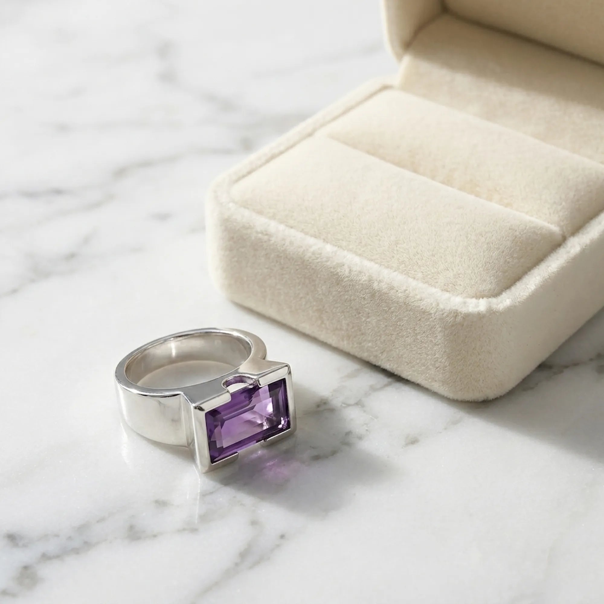 Natural amethyst cocktail ring on white marble beside open Luna Dura cream velvet gift box in soft studio light