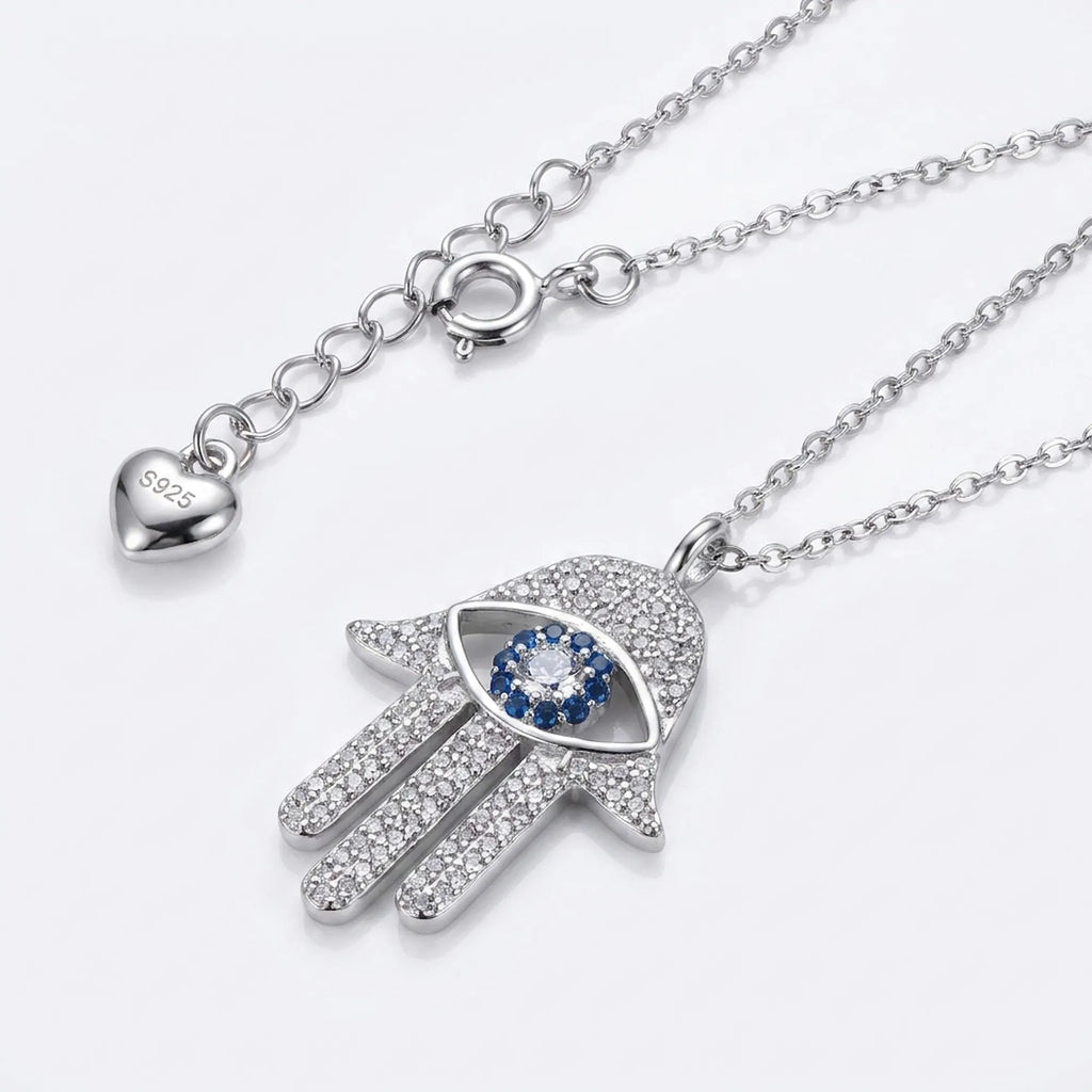 Silver necklace with Hamsa hand pendant featuring a blue gemstone on a white background