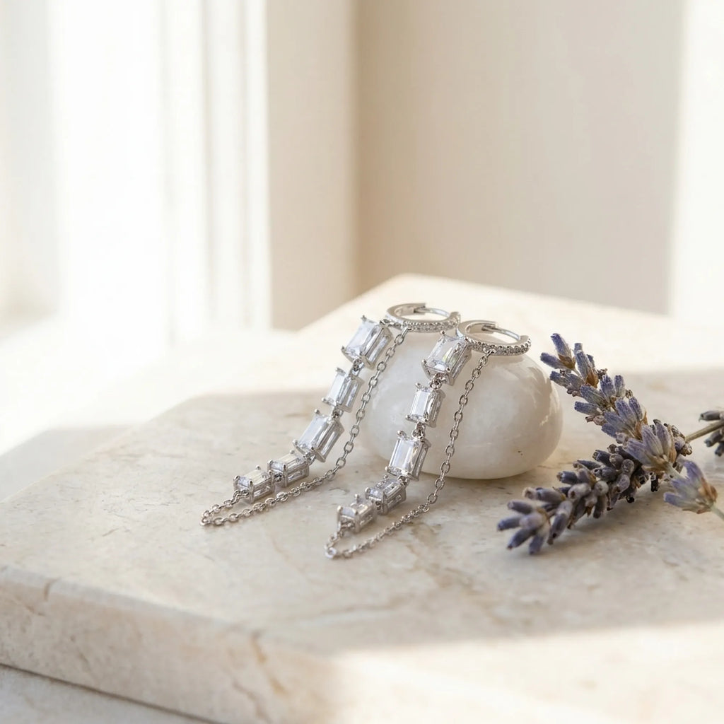 Baguette chain dangle earrings on marble surface with white ceramic and dried lavender — rhodium 925 silver CZ column and chain flat lay Dubai
