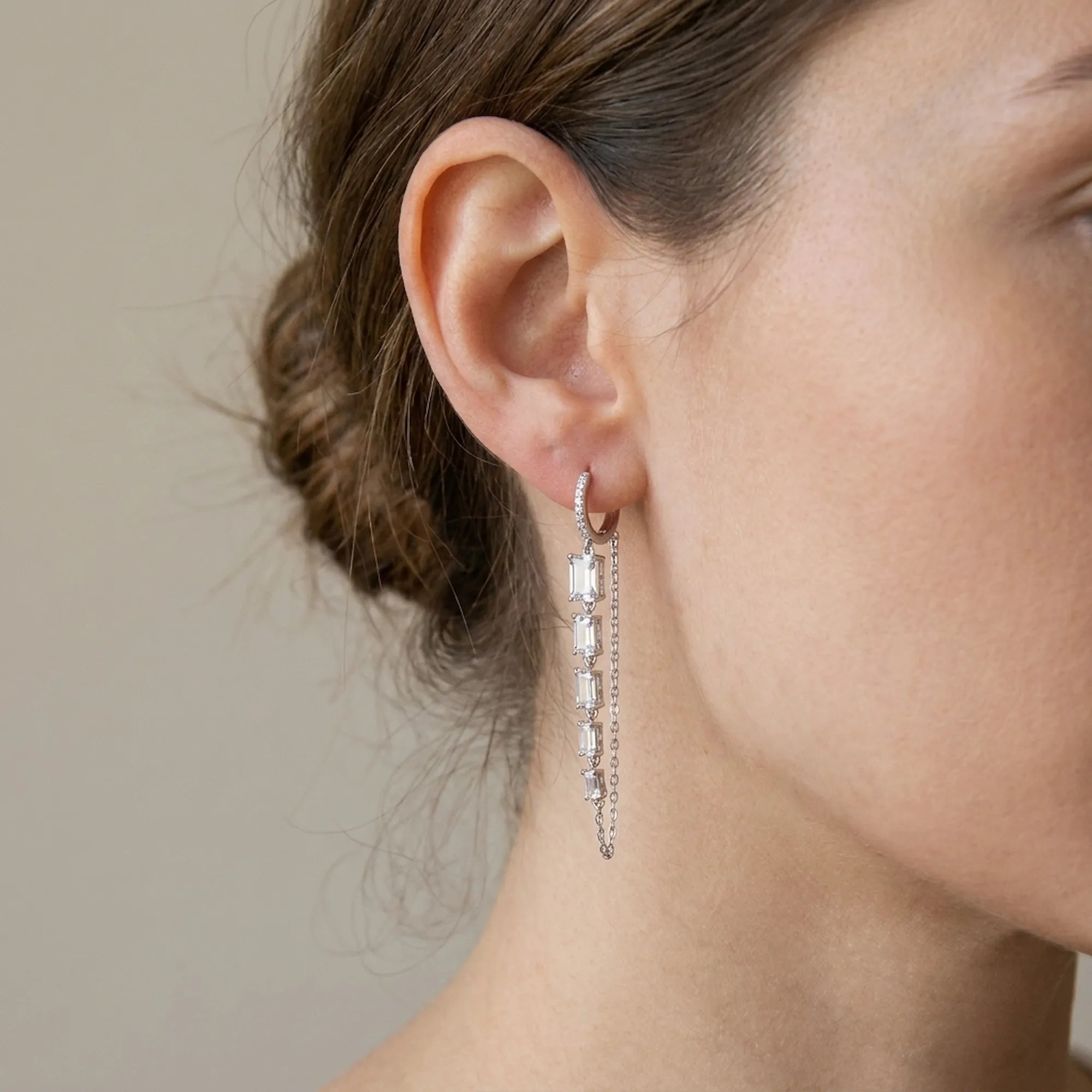 Close-up of baguette chain dangle earring on ear — full 59mm drop showing articulated CZ column and parallel cable chain, huggie hoop closure