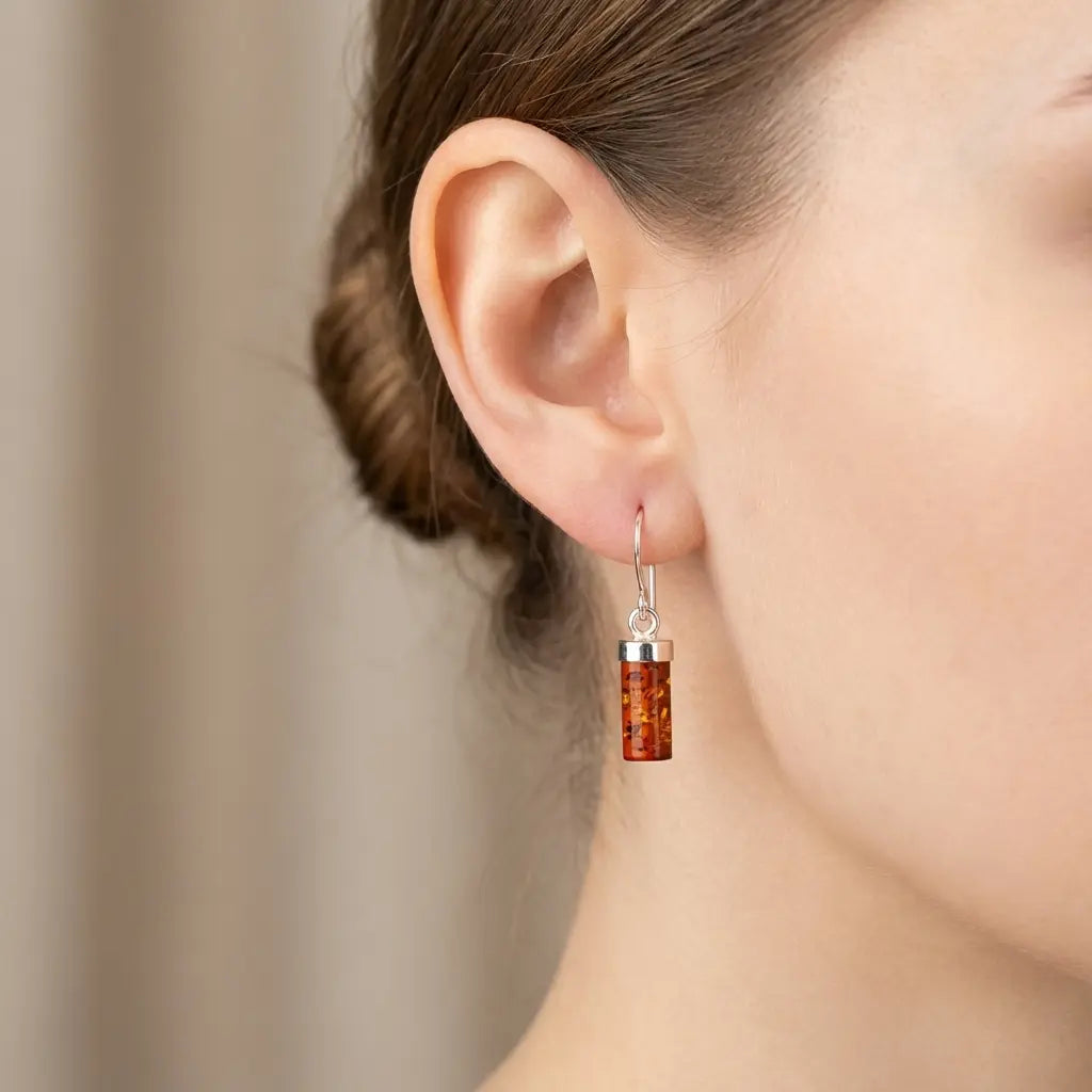 Baltic amber cylinder drop earrings in sterling silver shown on ear to demonstrate scale and elegant minimalist fit