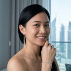 Woman smiling while wearing 925 silver bar drop earrings with French wire closures, set against the Jumeirah Emirates Towers Dubai.