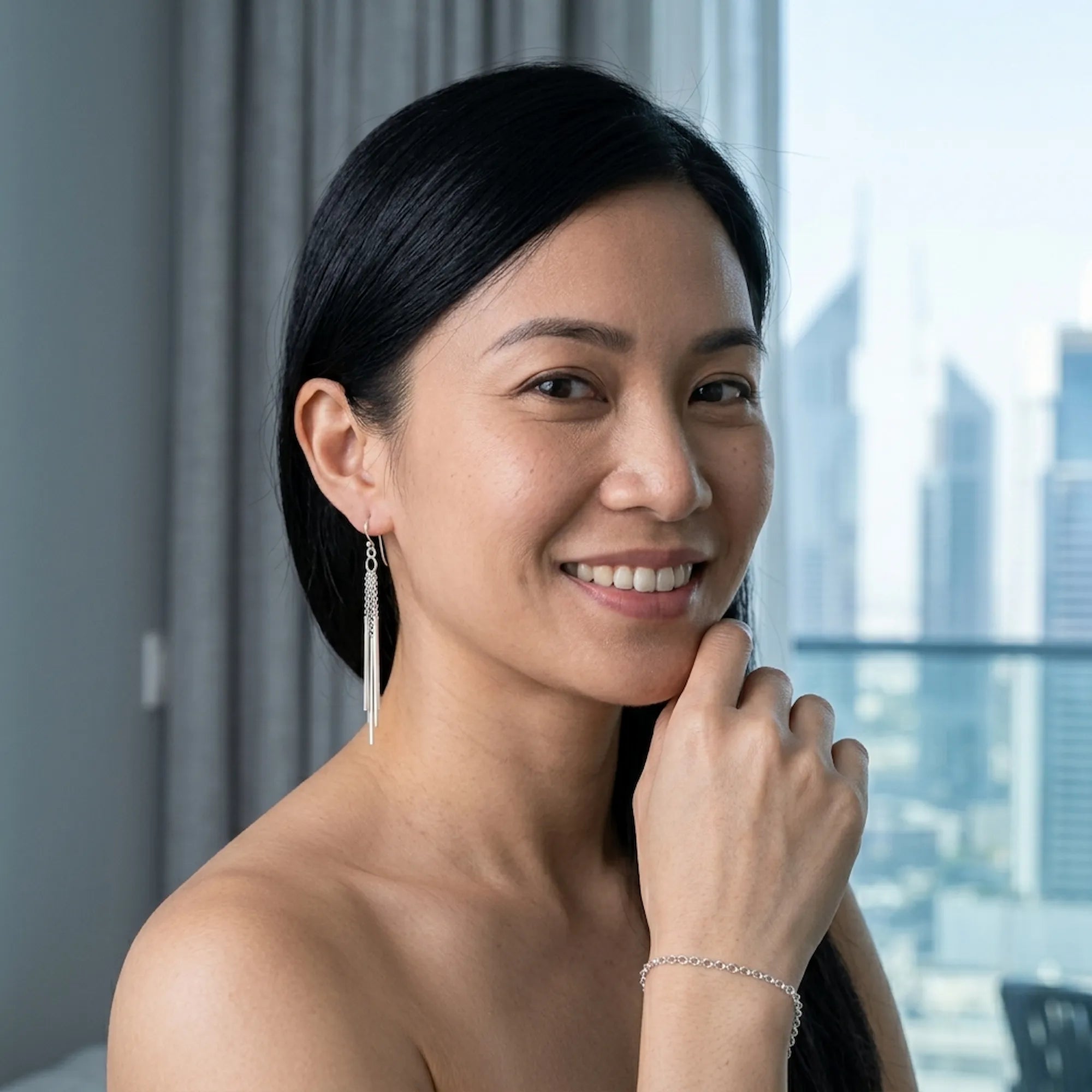 Woman smiling while wearing 925 silver bar drop earrings with French wire closures, set against the Jumeirah Emirates Towers Dubai.