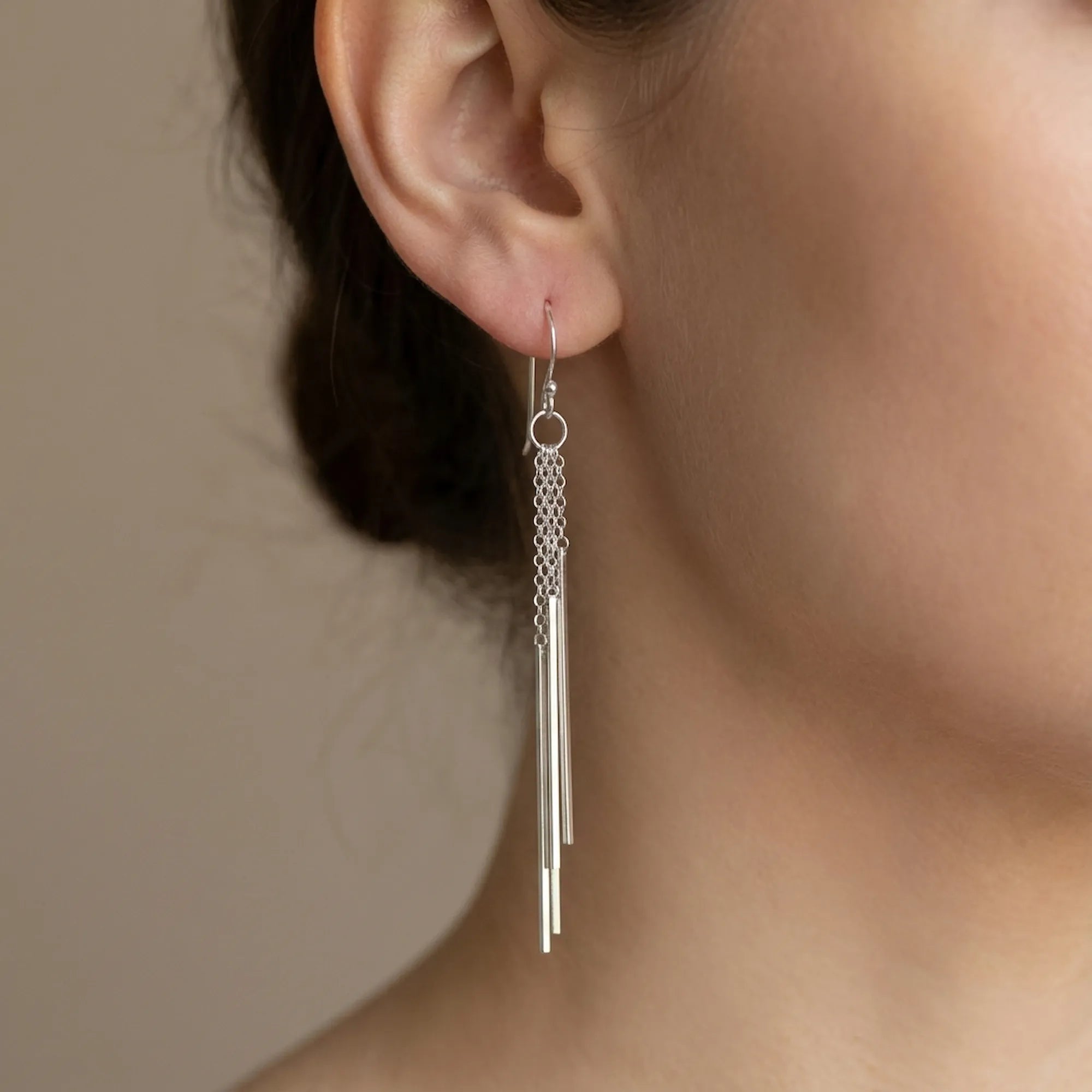 Sterling silver bar drop earring worn on the ear, cascading bars framing the jawline.