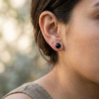 Single glossy black resin ball stud earring worn on the earlobe, showing the rounded 10 mm silhouette.
