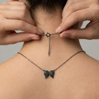 Hands seamlessly fastening the spring lock of the black rhodium plated pendant necklace, highlighting the 5cm extender chain fit.