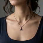Black cubic zirconia starfish necklace worn at the neckline with a dark top, showing the delicate chain and pendant scale.