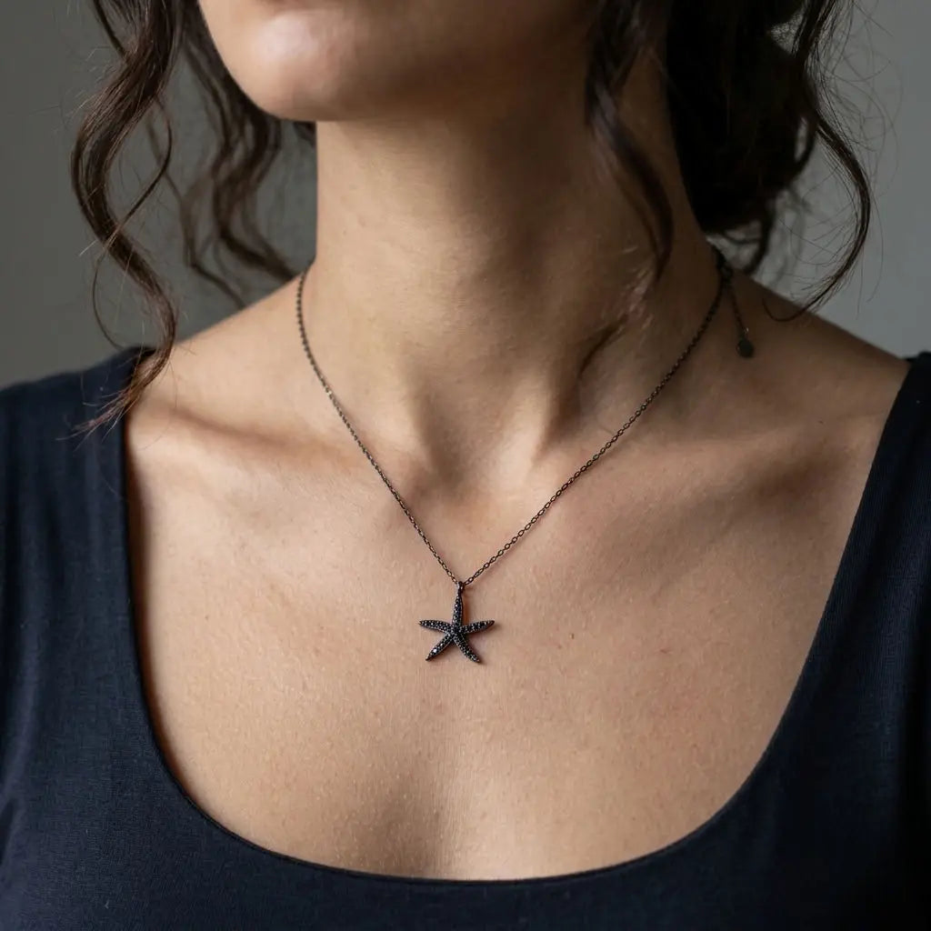 Black cubic zirconia starfish necklace worn at the neckline with a dark top, showing the delicate chain and pendant scale.