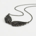 Side-angle view of the Black Zircon Wing Necklace showing the dimensional feather detail and black stones.