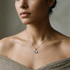 Small blue CZ evil eye necklace worn at the neckline on a 50 cm rhodium-plated 925 silver chain.