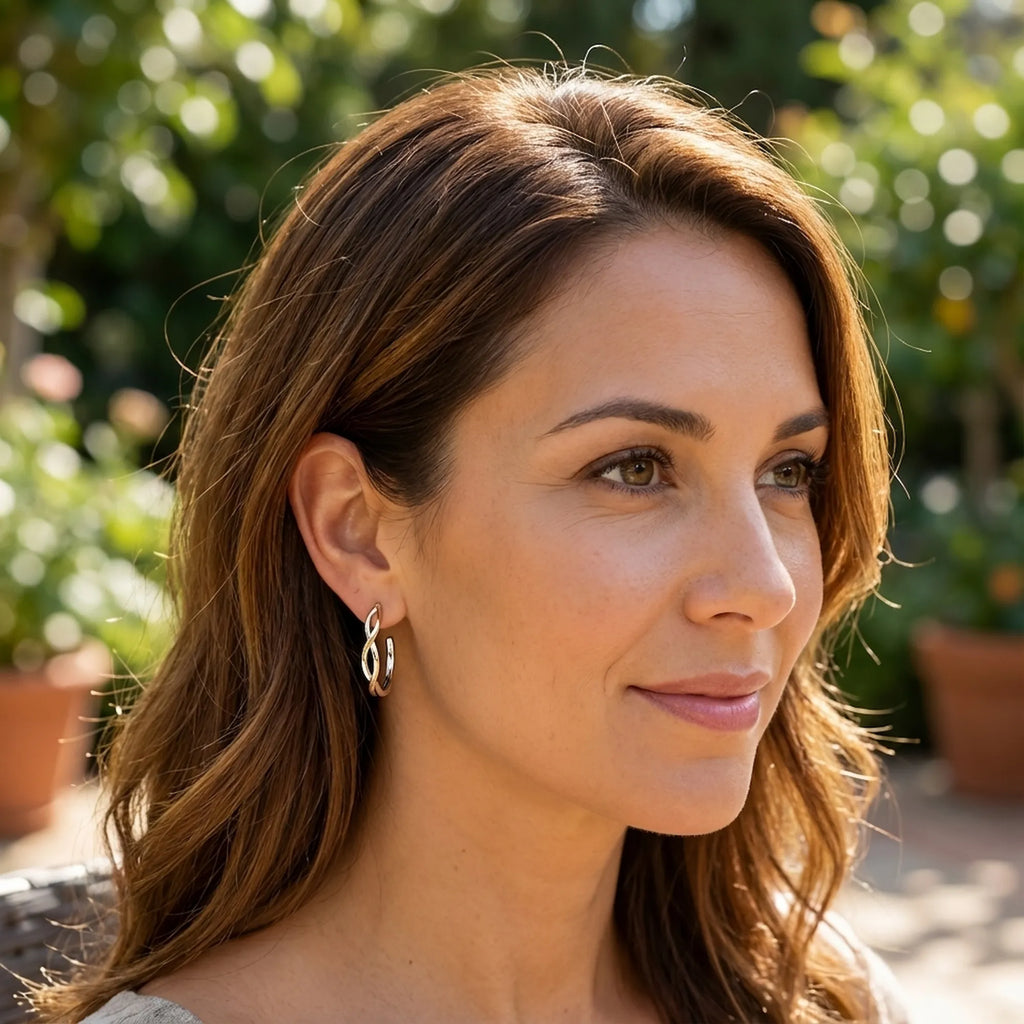 Two-tone silver and gold bypass hoop earring worn outdoors in natural light — sculptural interlaced wave, 925 sterling silver